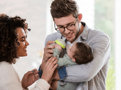 Jeunes parents souriants tenant leur bébé, illustrant le programme ADN et FSE+ pour la petite enfance d'aide aux familles.
