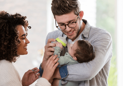 Jeunes parents souriants tenant leur bébé, illustrant le programme ADN et FSE+ pour la petite enfance d'aide aux familles.